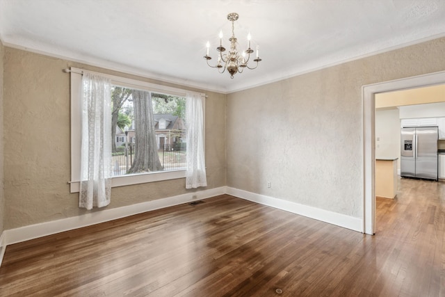 spare room featuring a notable chandelier, hardwood / wood-style flooring, and crown molding