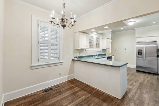 kitchen featuring dark hardwood / wood-style floors, kitchen peninsula, ornamental molding, white cabinets, and appliances with stainless steel finishes