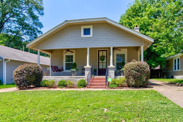 bungalow-style house featuring covered porch, a chimney, a front lawn, and ceiling fan
