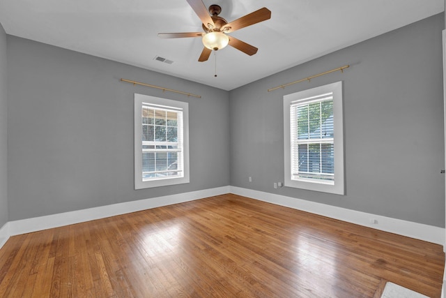 spare room featuring baseboards, a ceiling fan, visible vents, and wood finished floors
