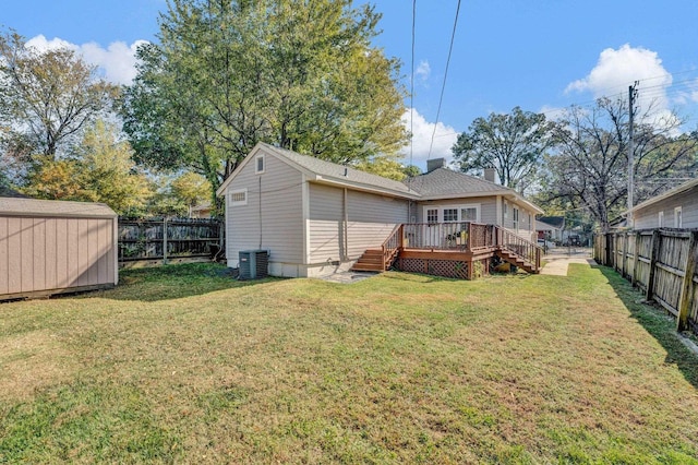 back of house with central air condition unit, a deck, an outbuilding, a fenced backyard, and a lawn