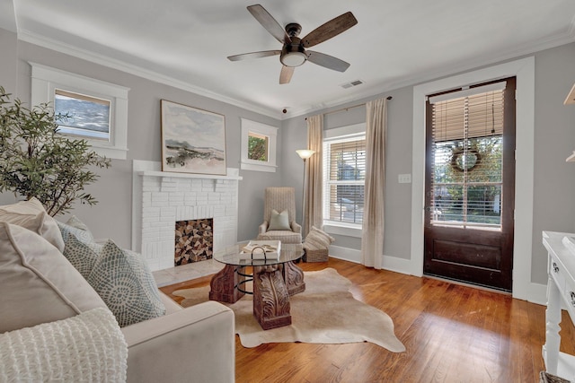 living room with light hardwood / wood-style floors, crown molding, a healthy amount of sunlight, and ceiling fan