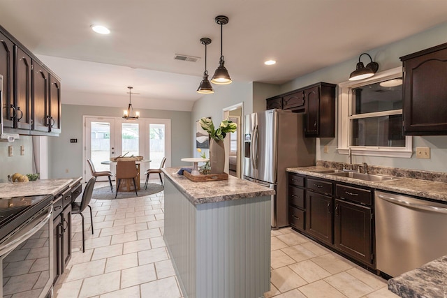 kitchen with appliances with stainless steel finishes, sink, dark brown cabinetry, decorative light fixtures, and light tile patterned floors