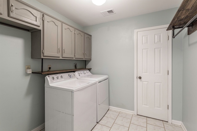 clothes washing area featuring cabinets, separate washer and dryer, and light tile patterned floors