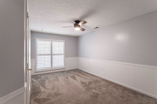 carpeted spare room featuring a textured ceiling and ceiling fan