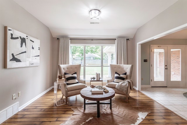 sitting room with lofted ceiling, french doors, and wood-type flooring