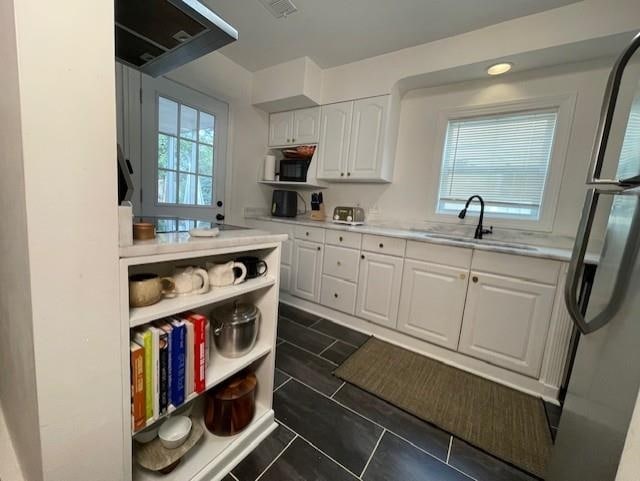 kitchen featuring stainless steel fridge, white cabinets, and sink