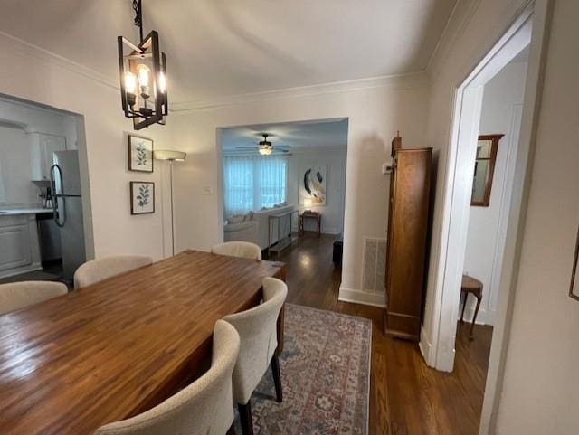 dining space with crown molding, dark hardwood / wood-style floors, and ceiling fan with notable chandelier