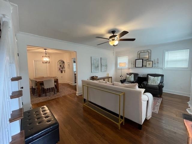 living room with plenty of natural light, crown molding, ceiling fan with notable chandelier, and dark hardwood / wood-style flooring