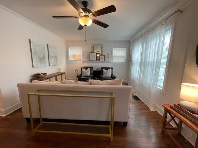 living room with crown molding, dark hardwood / wood-style floors, and ceiling fan