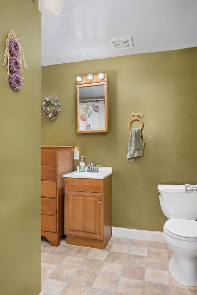 bathroom with toilet, vanity, and tile patterned floors