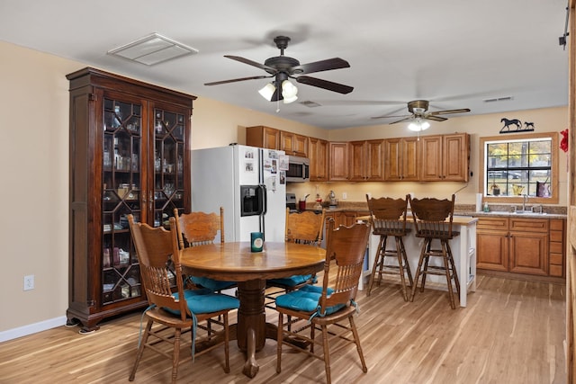 dining area with sink, light wood-type flooring, and ceiling fan