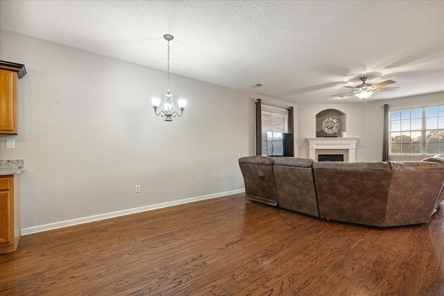 living room with dark hardwood / wood-style floors, a textured ceiling, and ceiling fan with notable chandelier