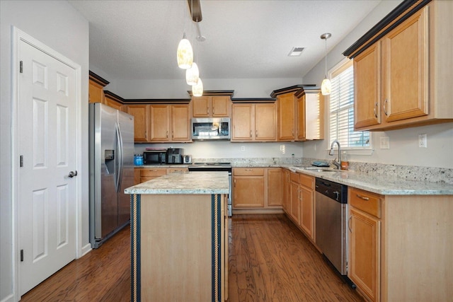 kitchen featuring appliances with stainless steel finishes, sink, dark wood-type flooring, and pendant lighting