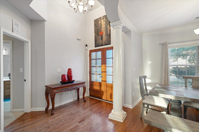 interior space featuring french doors, a chandelier, wood-type flooring, and decorative columns