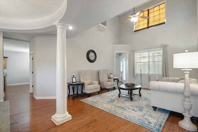 living room featuring hardwood / wood-style floors, high vaulted ceiling, ornate columns, and ceiling fan