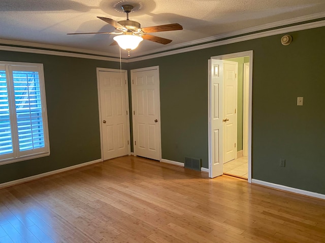 unfurnished bedroom featuring ceiling fan, ornamental molding, a textured ceiling, and light wood-type flooring