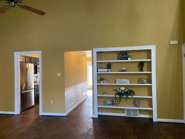 interior space featuring dark wood-type flooring, a high ceiling, and ceiling fan