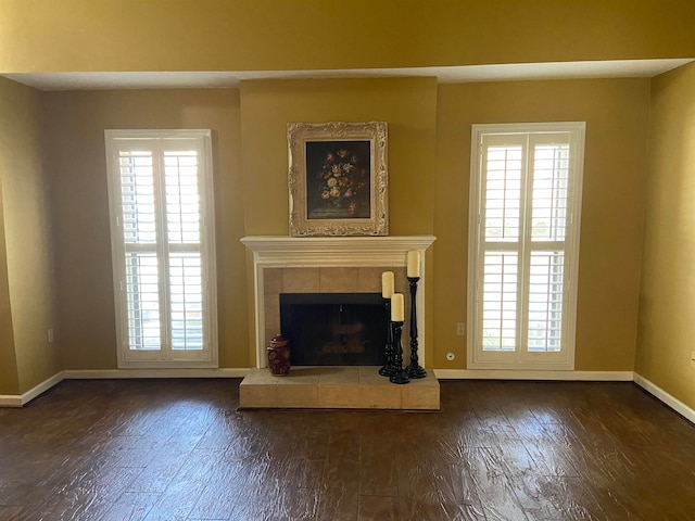 unfurnished living room with a healthy amount of sunlight, a tile fireplace, and dark hardwood / wood-style flooring