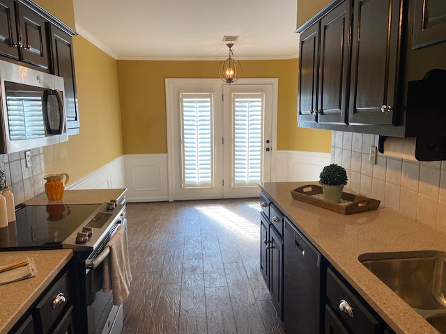 kitchen with tasteful backsplash, stainless steel appliances, decorative light fixtures, ornamental molding, and dark hardwood / wood-style floors