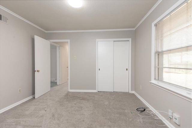 unfurnished bedroom featuring a closet, ornamental molding, light colored carpet, and a textured ceiling