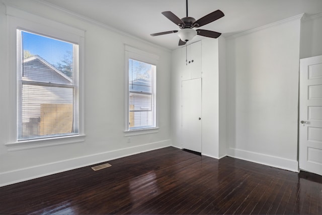 unfurnished bedroom featuring dark wood-type flooring, crown molding, multiple windows, and ceiling fan