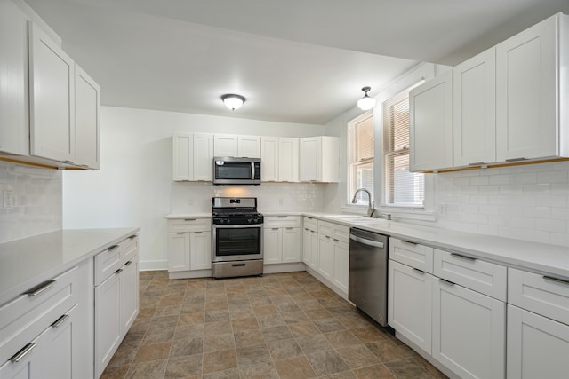 kitchen featuring white cabinets, stainless steel appliances, sink, and backsplash