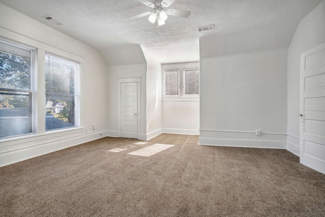 unfurnished room featuring light carpet, a textured ceiling, lofted ceiling, and ceiling fan