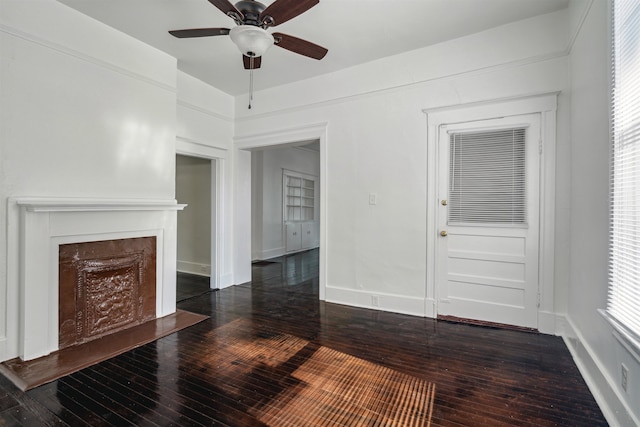 unfurnished living room featuring dark wood-type flooring and ceiling fan