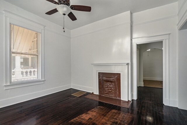 2186 Monroe Ave, Memphis, TN 38104 - unfurnished living room featuring ceiling fan, hardwood / wood-style flooring, arched walkways, baseboards, and a fireplace