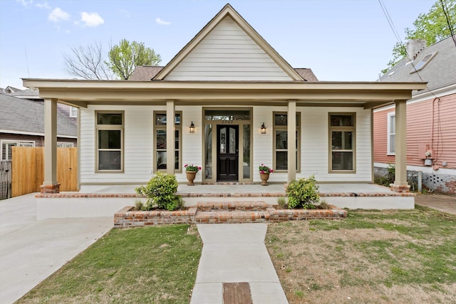 view of front of home featuring a porch, fence, and a front yard