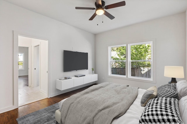 bedroom featuring baseboards, multiple windows, a ceiling fan, and wood finished floors