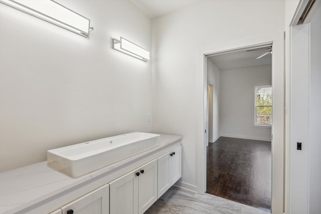 bathroom with ceiling fan, baseboards, and wood finished floors