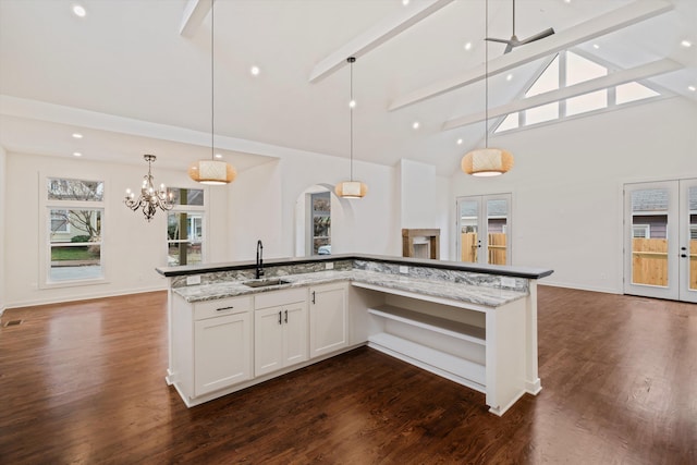 kitchen with a sink, arched walkways, high vaulted ceiling, and plenty of natural light