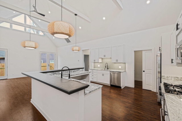 kitchen with beam ceiling, a sink, high vaulted ceiling, stainless steel appliances, and a large island with sink