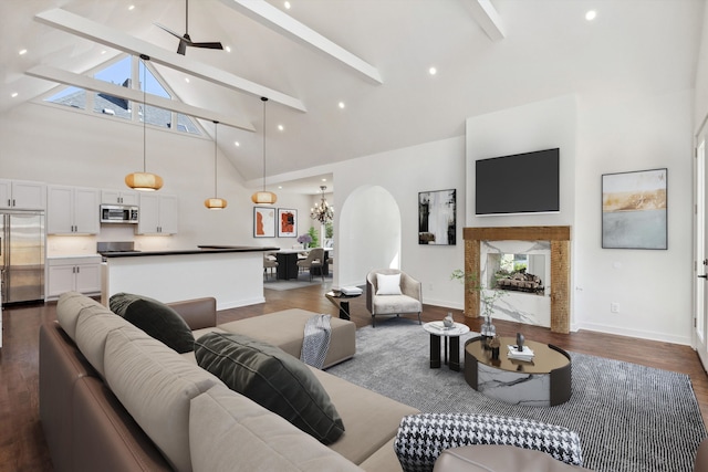 living area with ceiling fan with notable chandelier, high vaulted ceiling, beamed ceiling, dark wood-style floors, and baseboards