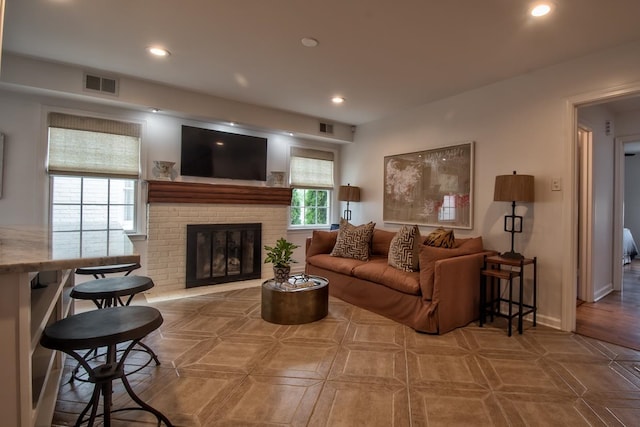 living room featuring plenty of natural light and a brick fireplace