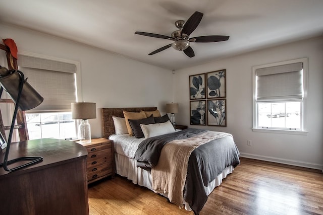 bedroom featuring multiple windows, hardwood / wood-style floors, and ceiling fan