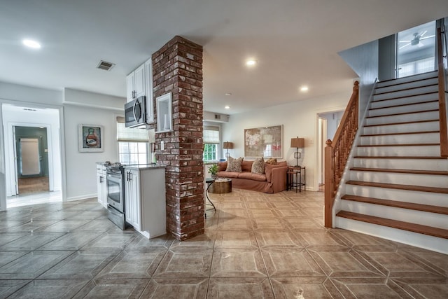 kitchen with white cabinetry, appliances with stainless steel finishes, decorative columns, and a breakfast bar area