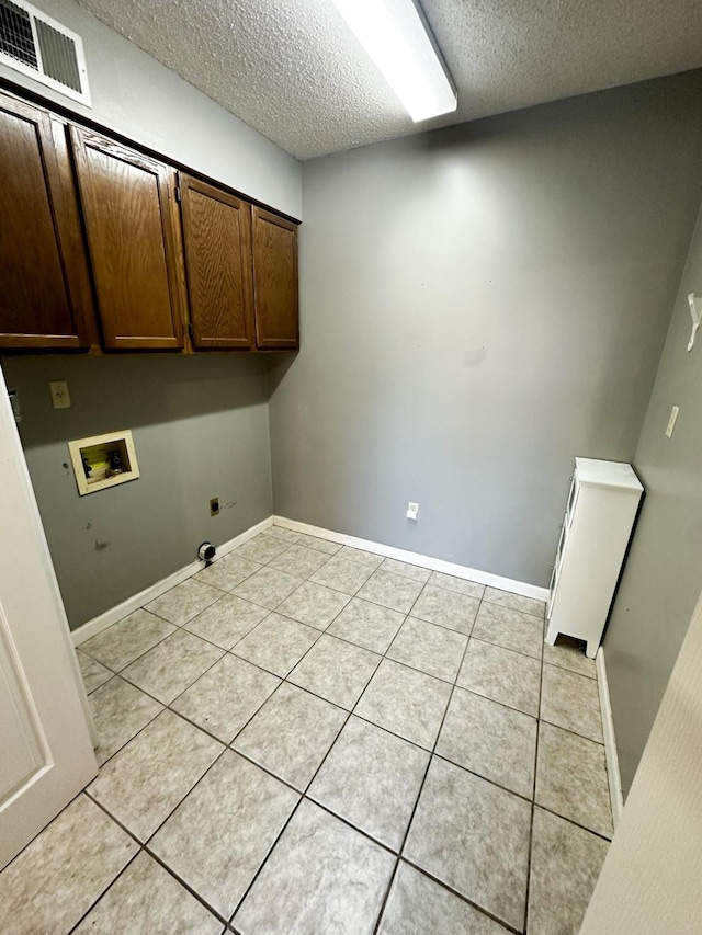 washroom featuring electric dryer hookup, washer hookup, light tile patterned floors, and cabinets