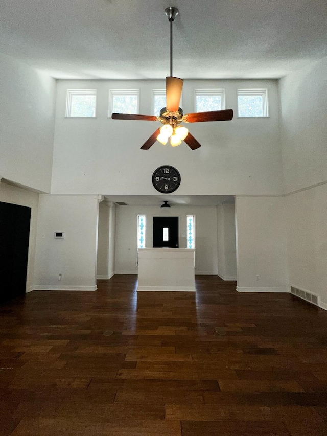 unfurnished living room with dark hardwood / wood-style floors, a textured ceiling, plenty of natural light, and ceiling fan