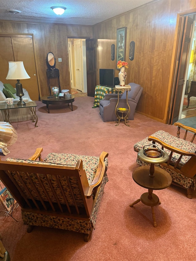 carpeted living room featuring wood walls and a textured ceiling