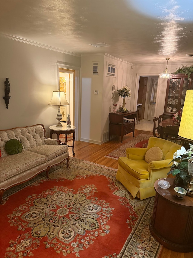 living room with ornamental molding, hardwood / wood-style flooring, and a chandelier