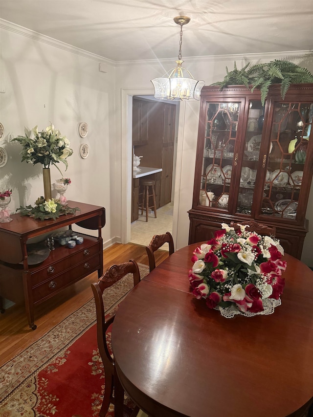 dining room with light hardwood / wood-style floors, a notable chandelier, and ornamental molding