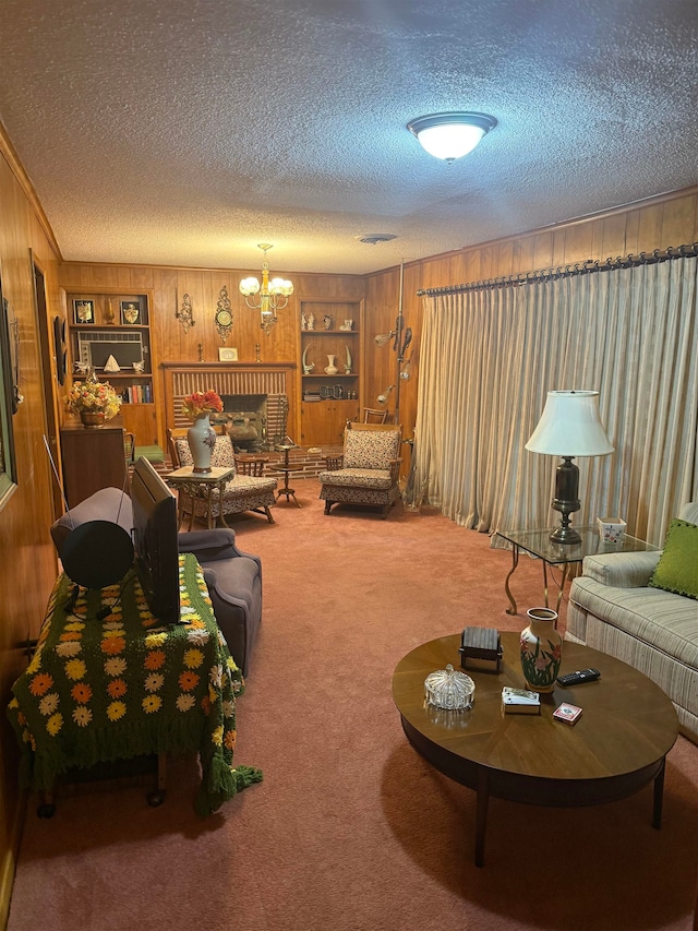 carpeted living room featuring a fireplace, a notable chandelier, built in features, a textured ceiling, and wood walls