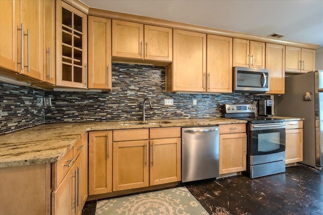 kitchen with appliances with stainless steel finishes, tasteful backsplash, sink, and light stone counters