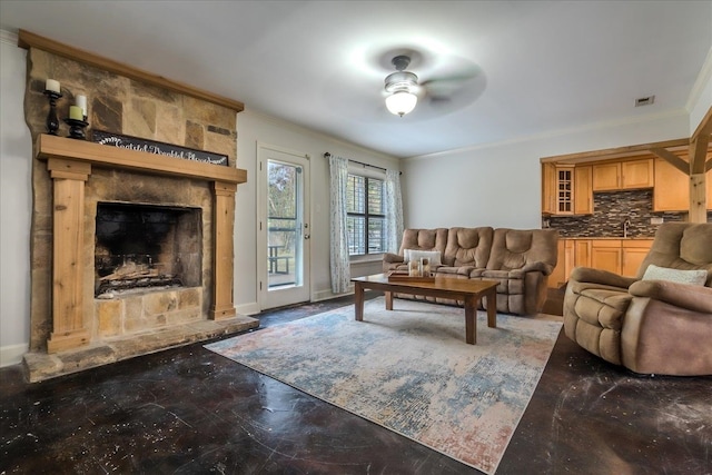 living room with crown molding, sink, a fireplace, and ceiling fan