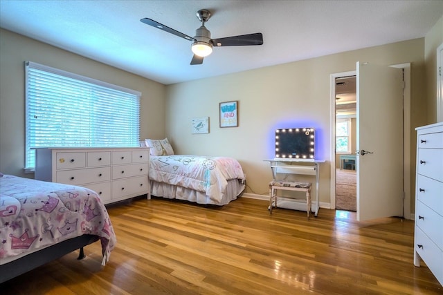 bedroom featuring light hardwood / wood-style flooring, ceiling fan, and multiple windows