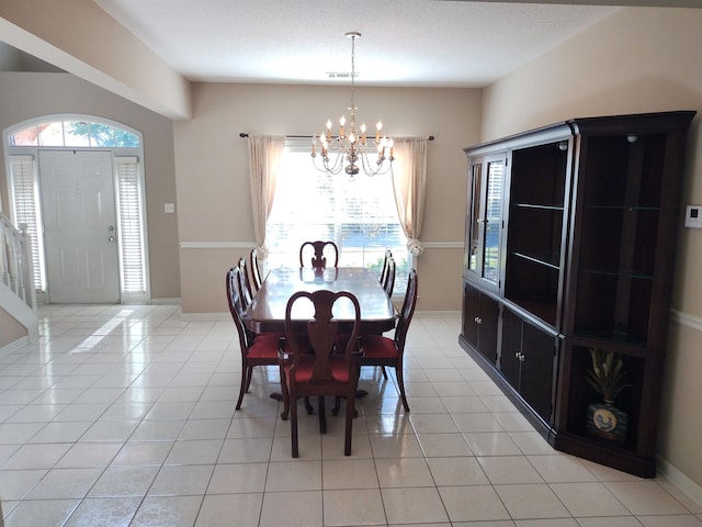 tiled dining room with a healthy amount of sunlight, a textured ceiling, and a notable chandelier