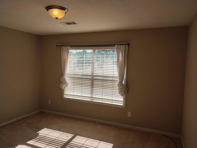 carpeted spare room with a textured ceiling